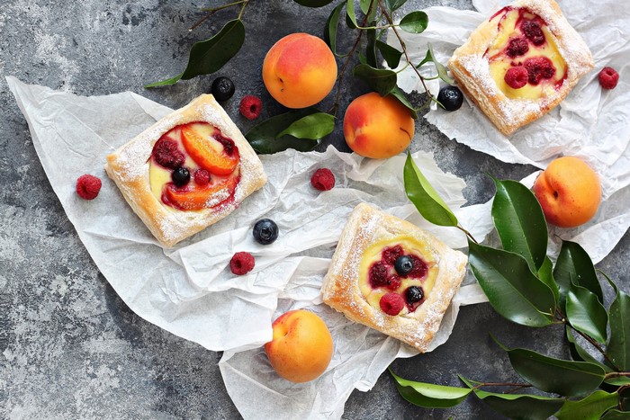 Fruit tarts with peaches and berries on parchment paper