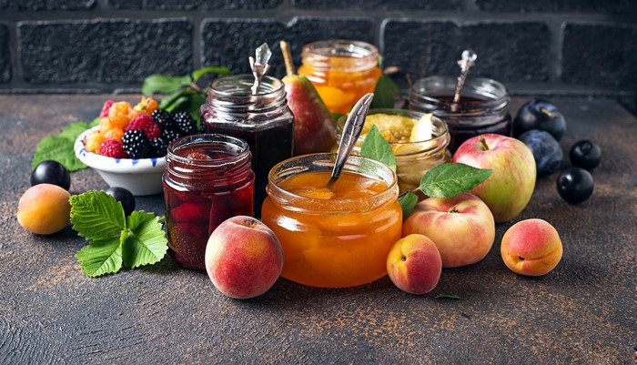 Jars of fruit jam with fresh fruits and mint leaves
