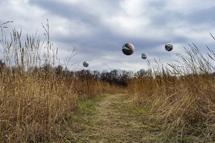 Volleyballs floating over a grassy field