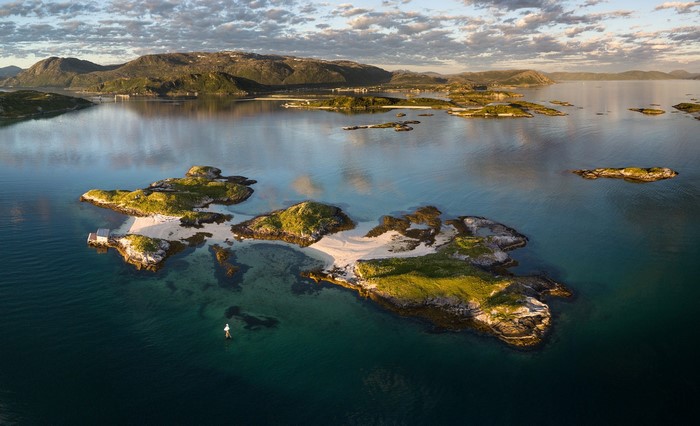 Islands in a calm bay with a person on a paddleboard