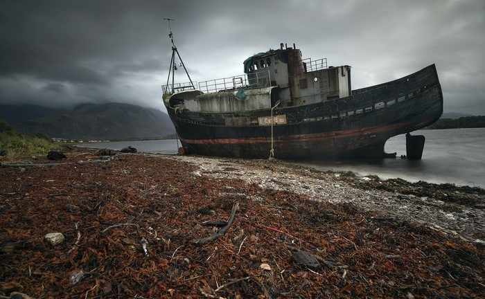 Abandoned shipwreck on a rocky shore under stormy skies