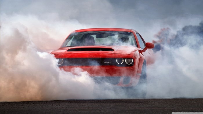 Red Dodge Challenger SRT doing a burnout in smoke