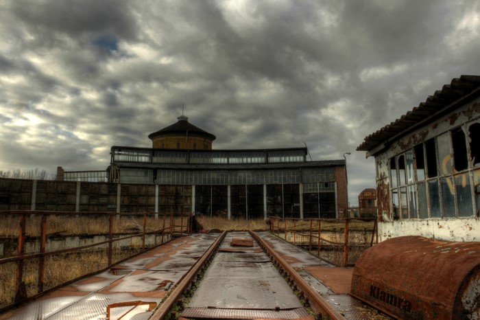 Abandoned rail yard with roundhouse under cloudy sky