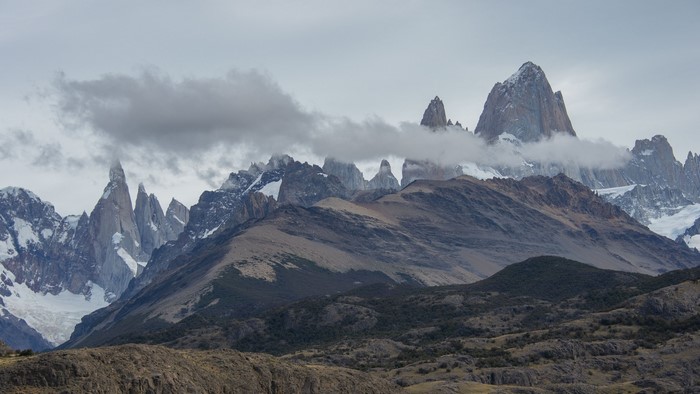 Jagged mountains shrouded in clouds under a grey sky