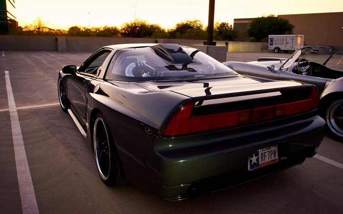 Dark Honda NSX in a parking lot at sunset