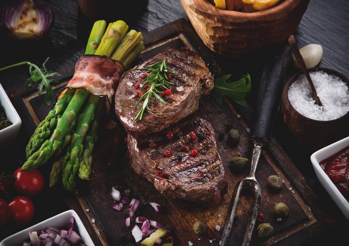 Grilled steaks with bacon-wrapped asparagus and sides
