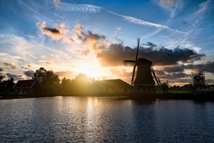 Sunset over canal with windmill in Netherlands