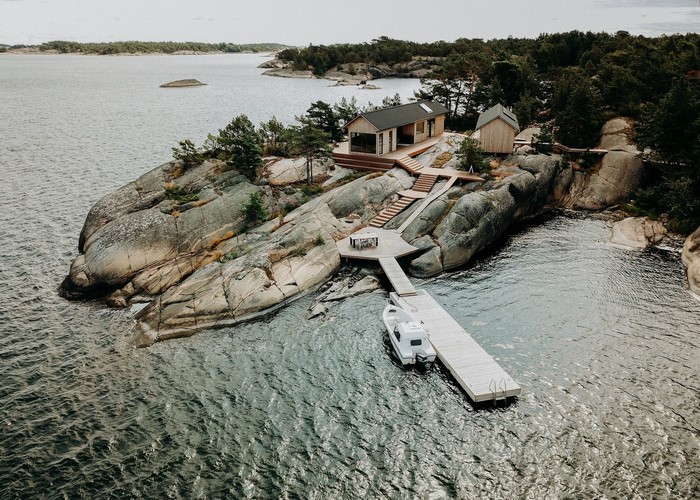 Modern cabins on a rocky island with a pier and boat