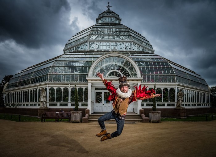 Man in costume jumping in front of a glass building
