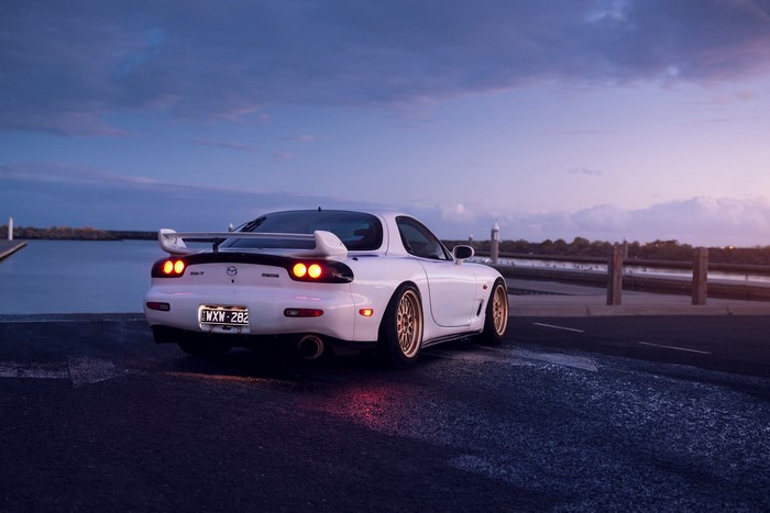 White Mazda RX-7 FD with gold wheels at dusk