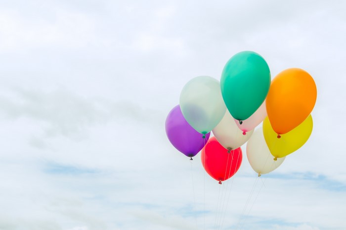 A cluster of colorful balloons against a cloudy sky