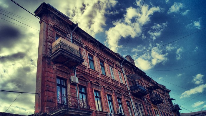 Old building facade with balconies against a cloudy sky