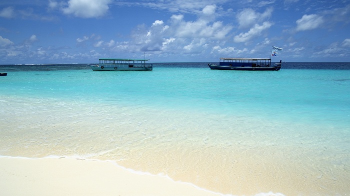 Boats on turquoise water near a sandy beach