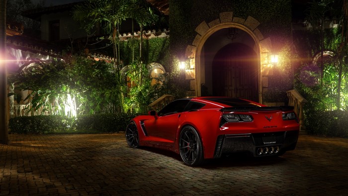 Red Chevrolet Corvette parked in front of a house at night
