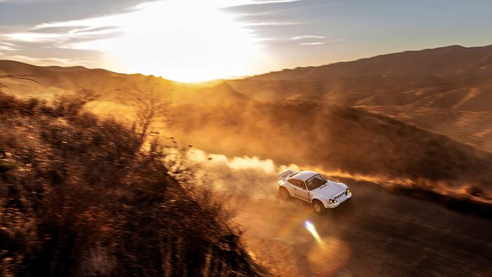 White Porsche 911 rally car driving through desert dust