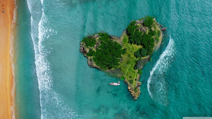 Heart-shaped island with trees and a boat