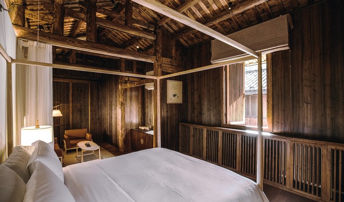 Rustic wooden bedroom with canopy bed and sitting area