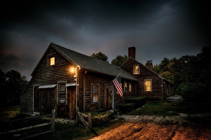 Old wooden house with American flag at dusk