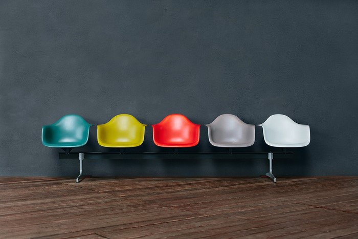 Colorful chairs on a bench in front of a dark wall