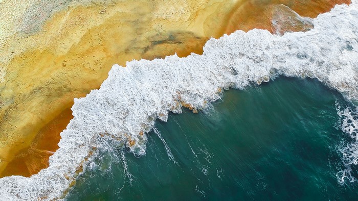 Aerial view of waves crashing on a sandy beach