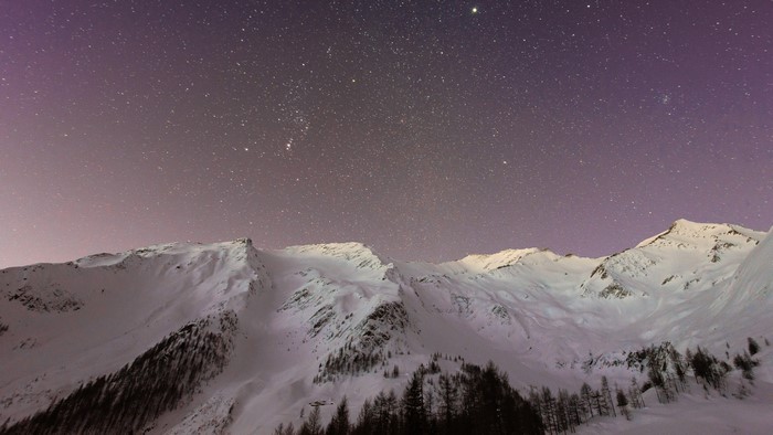 Snowy mountains under a starry night sky