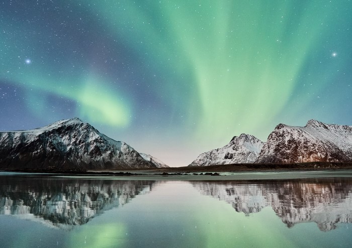 Aurora Borealis over snow-capped mountains reflected in water