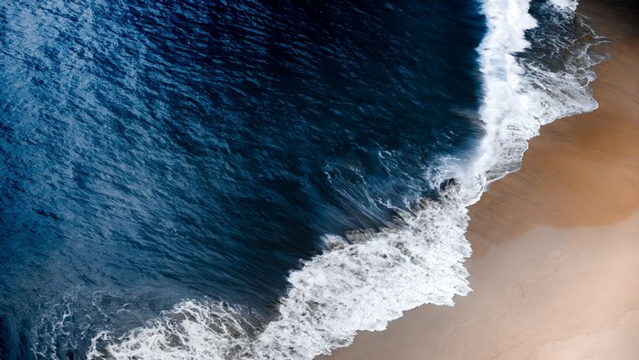 Top view of ocean waves crashing on a sandy beach