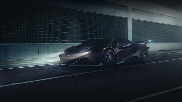 Dark Lamborghini sports car with spoiler on road