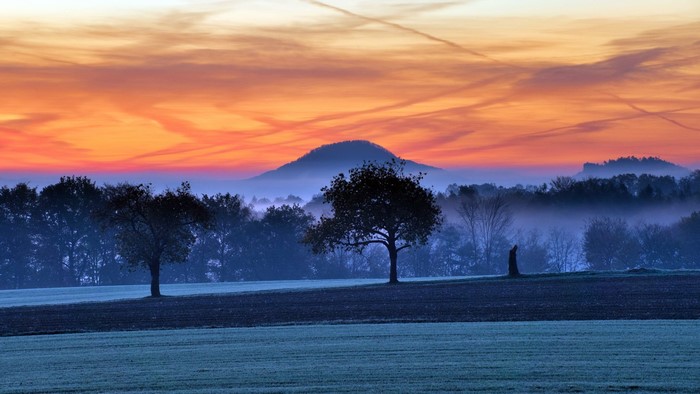 Misty landscape at sunset with a lone figure