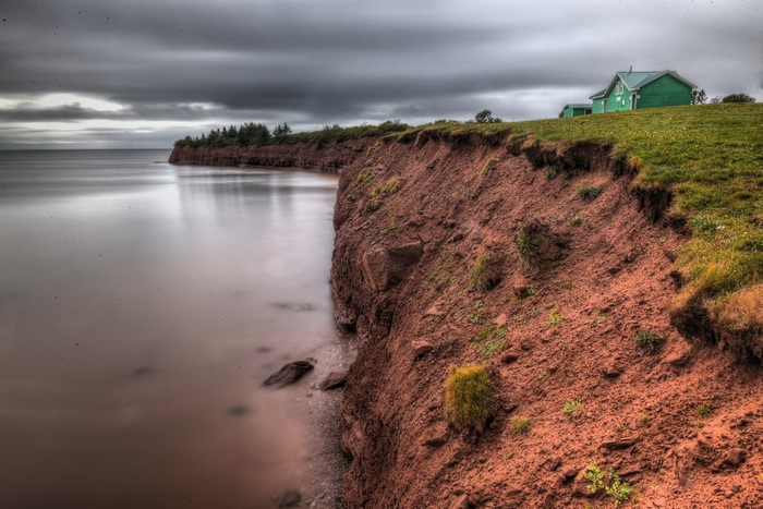 Green house on a cliff overlooking the ocean