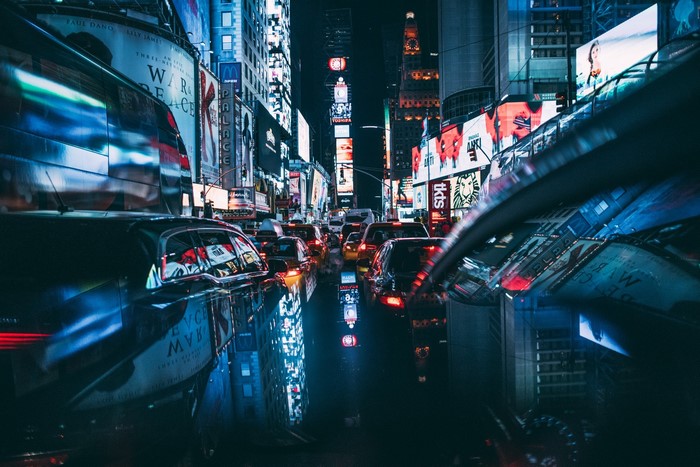 Times Square traffic at night with illuminated billboards