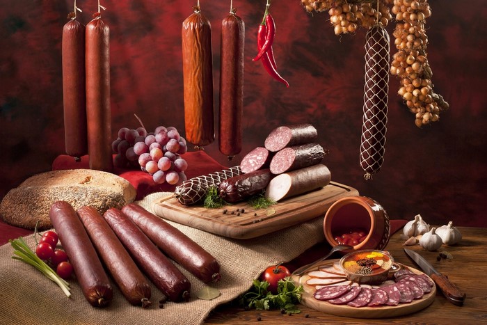 Sausages, bread, grapes, and chili peppers on a table