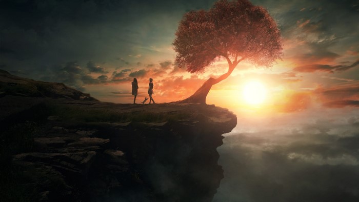 Two people and a tree on a cliff at sunset