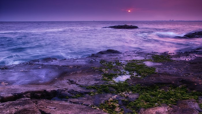 Long exposure sunset over rocky coast with purple sky