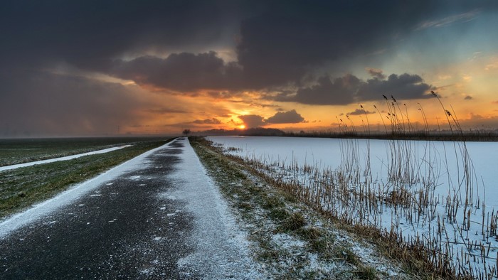 Winter sunset over a frozen landscape with a road
