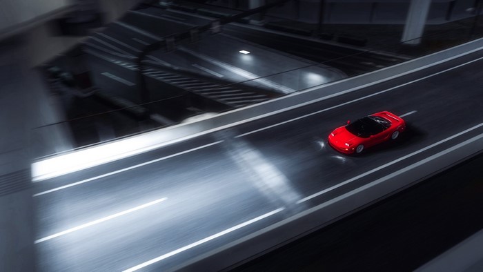 Red sports car driving on a highway at night