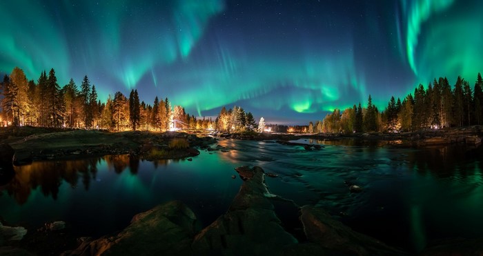 Aurora Borealis over a forest and river at night