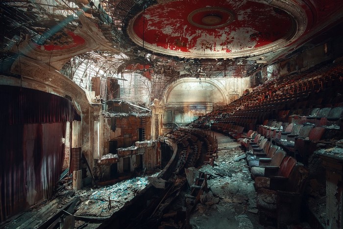 Abandoned theater interior with decaying seats and stage