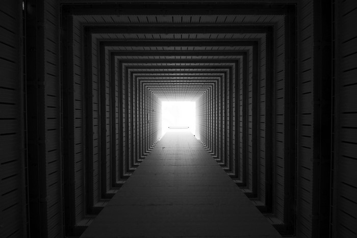 Monochrome square hallway leading to bright light