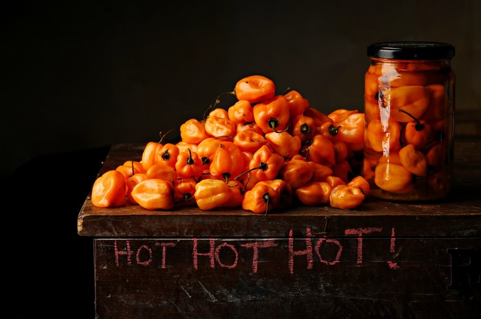 Orange habanero peppers in a jar and a pile