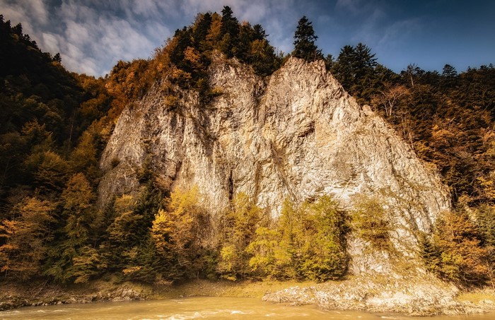 Rocky cliff face with autumn trees and river