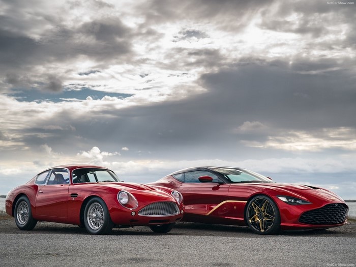 Two red Aston Martin sports cars, one classic and one modern