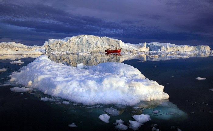 Red boat among icebergs in the Arctic