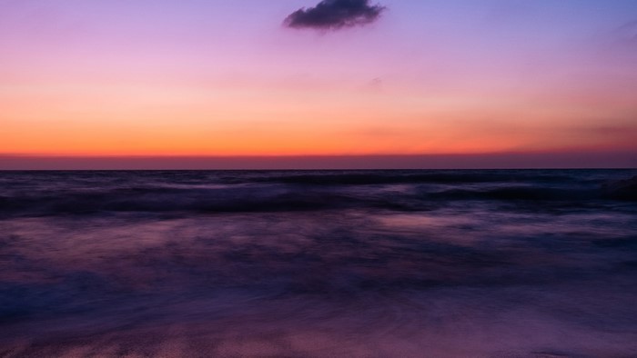 Ocean waves at sunset with purple and orange sky