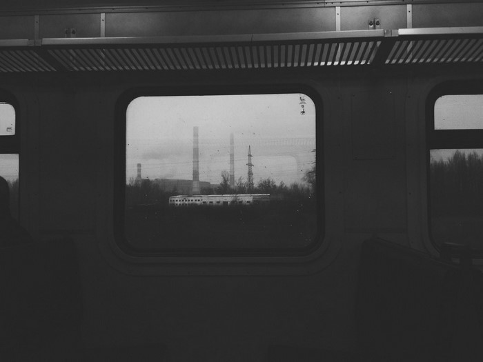 Train window view of industrial landscape in monochrome