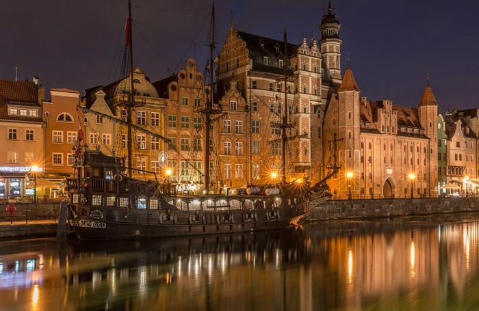 Night view of a historic ship docked by buildings in Gdansk, Poland