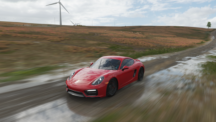 Red Porsche Cayman driving on a dirt road in Forza Horizon 4
