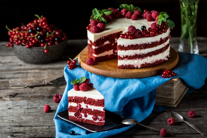Red velvet cake with berries and mint on a wooden surface