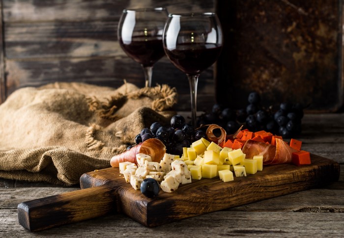 Wine and cheese board with grapes on a wooden surface