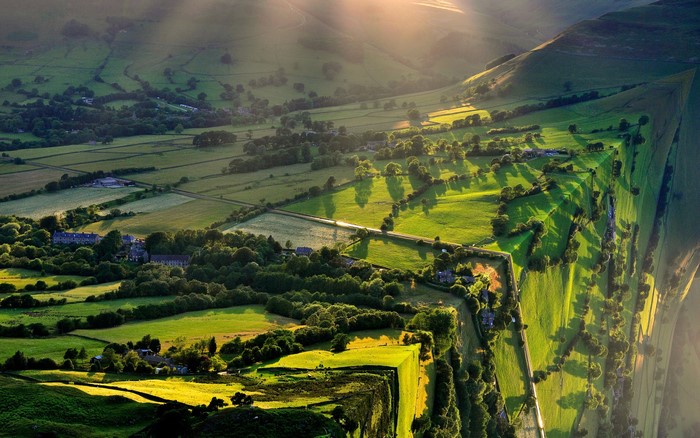 Aerial view of a sunlit green valley with fields and trees